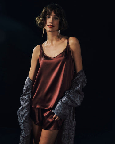 Woman wearing a burgundy satin shorts set with a dark background